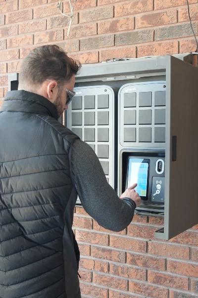 Hombre pulsando la pantalla de un SmartBox instalado en el exterior de un edificio.
