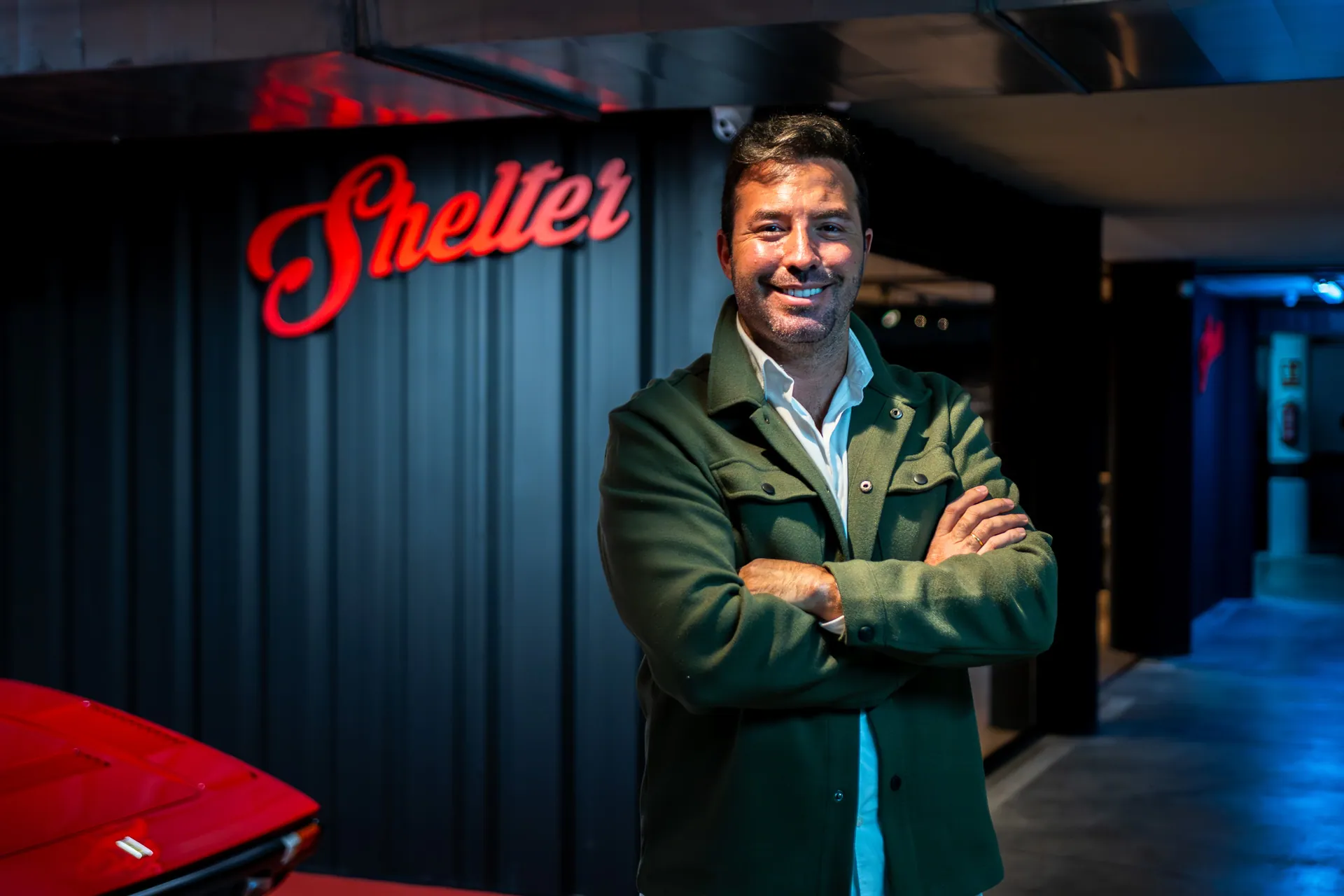 Iván Fiestas standing next to the Shelter logo inside their facility