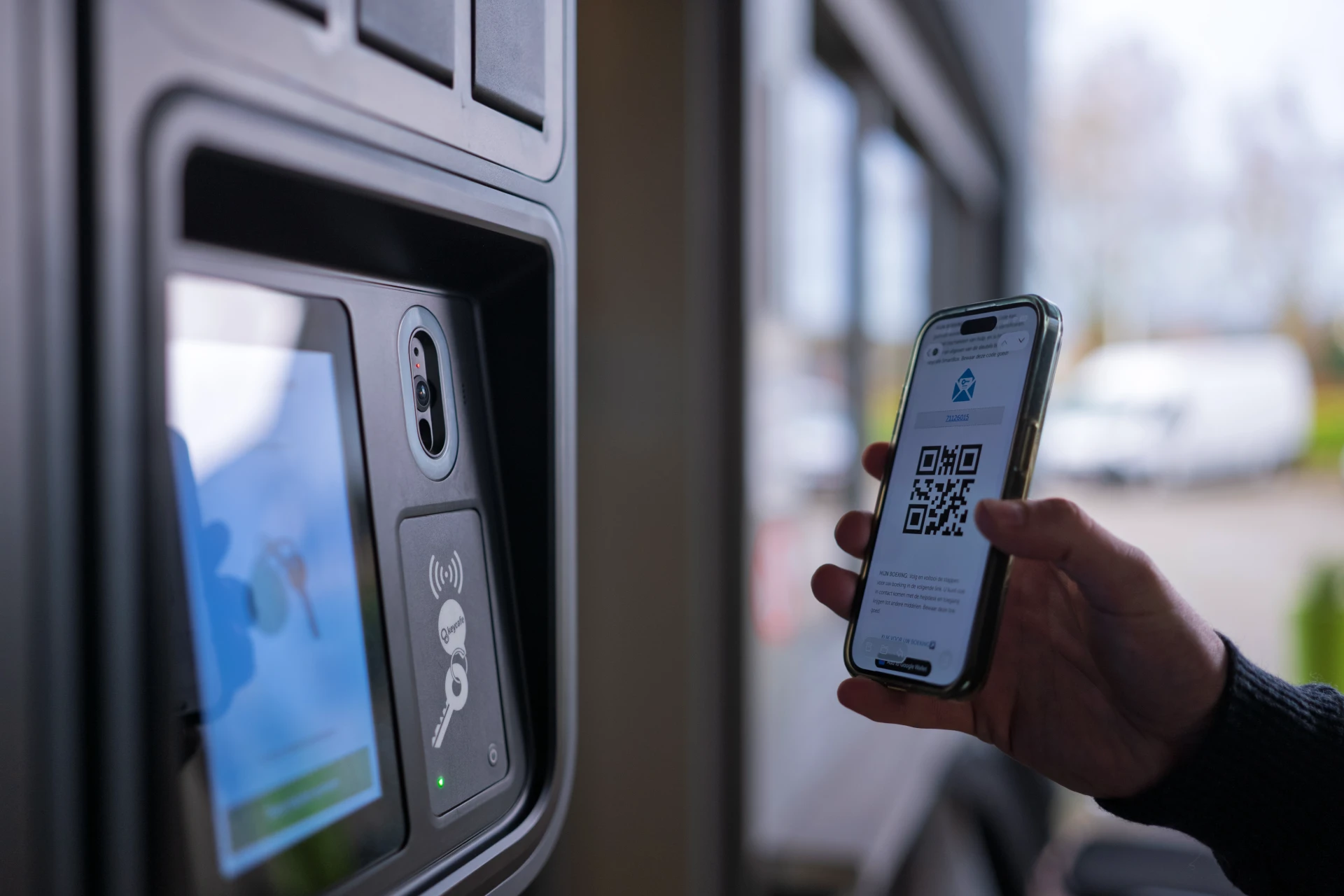 A hand presenting a smartphone with a QR code on the screen to a SmartBox camera