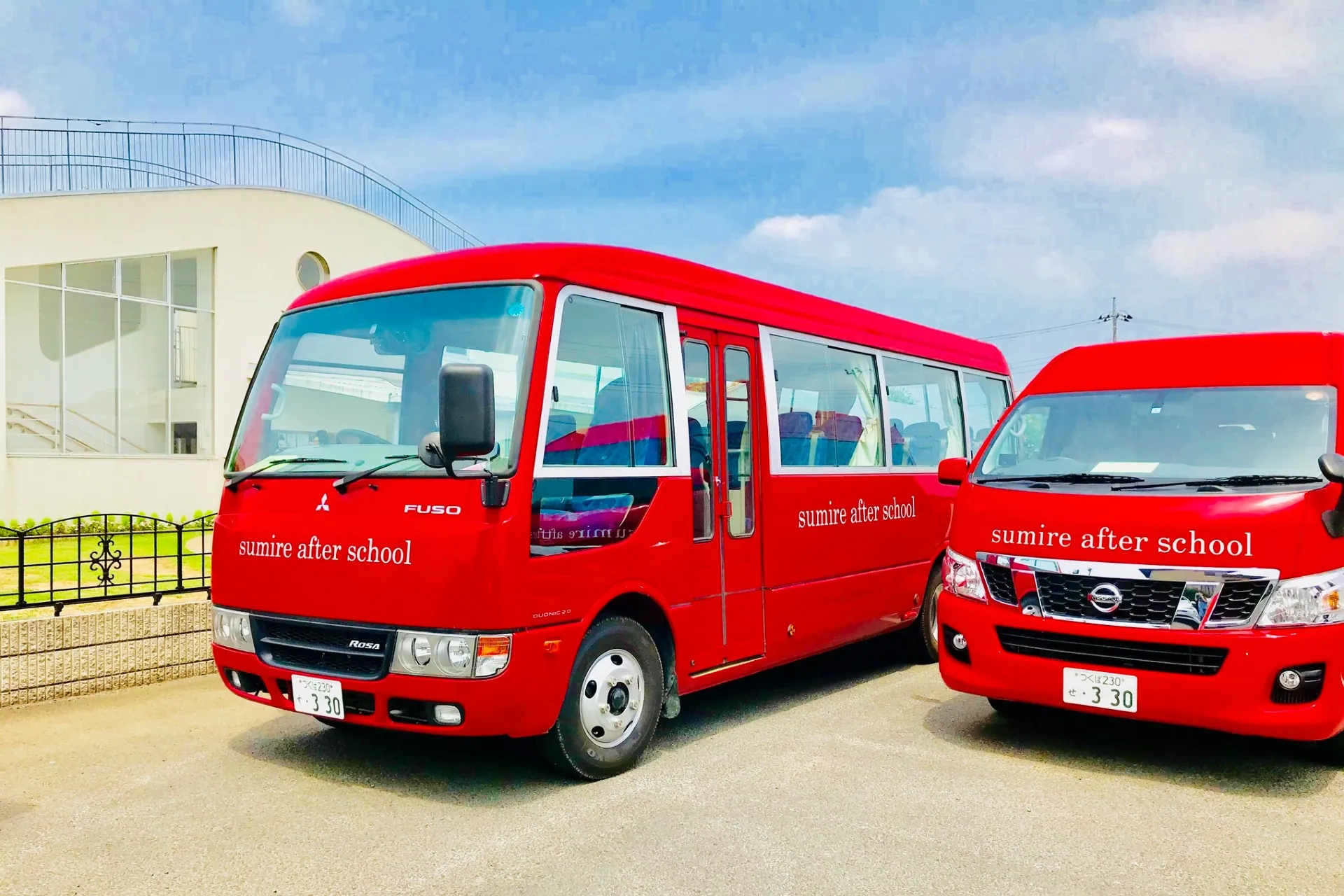 Two red Kindergarten Sumire school buses parked outside