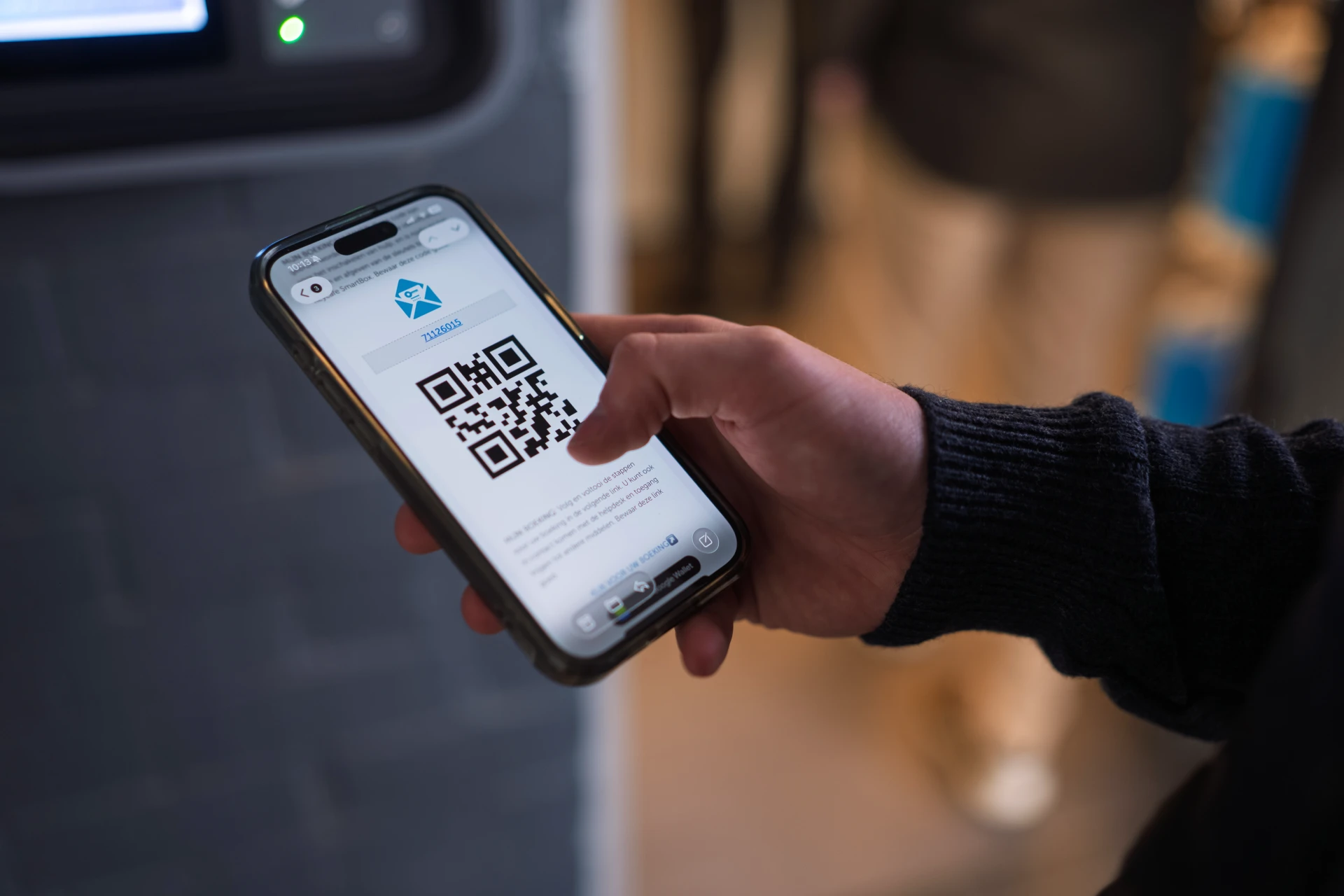 Hand holding a smartphone with a Keycafe booking QR code on the screen