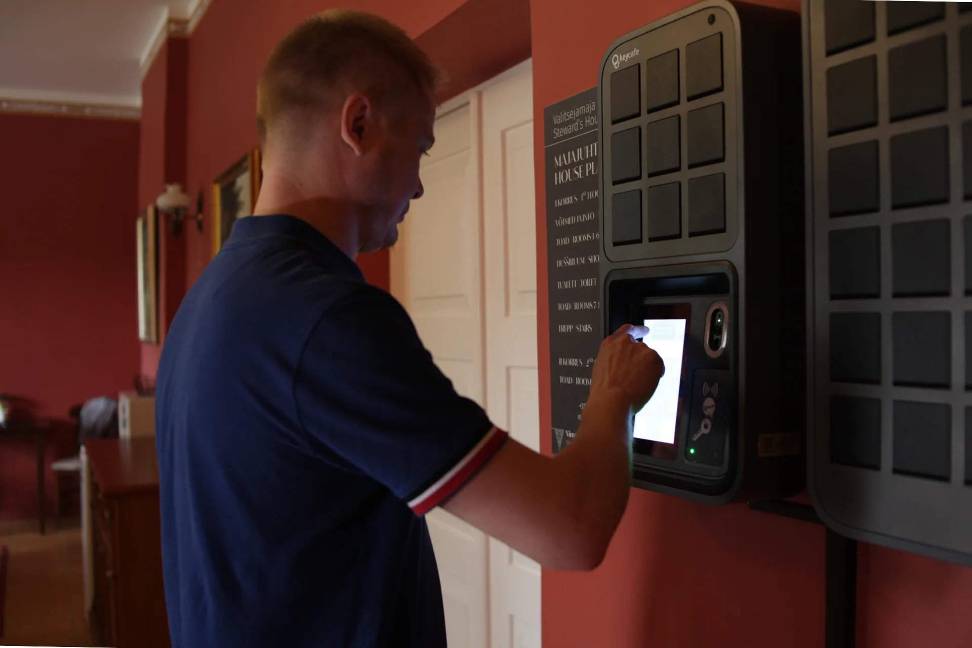 Guest using Keycafe SmartBox automated key management system for self check-in at Palmse Manor guest house in Estonia.