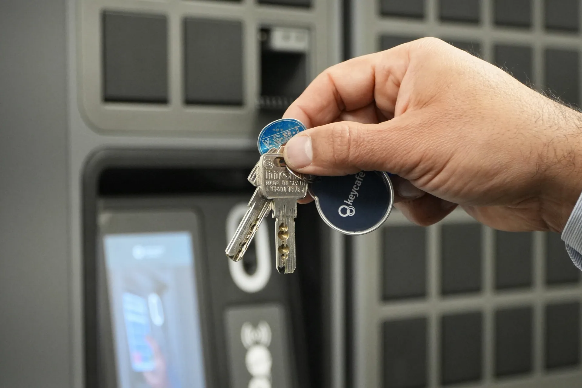 Close-up of a hand holding airport keys attached to a Keycafe fob