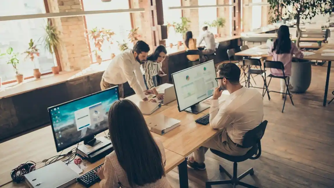 Coworking Space with workers gathered around a computer, they used Keycafe to access the space.