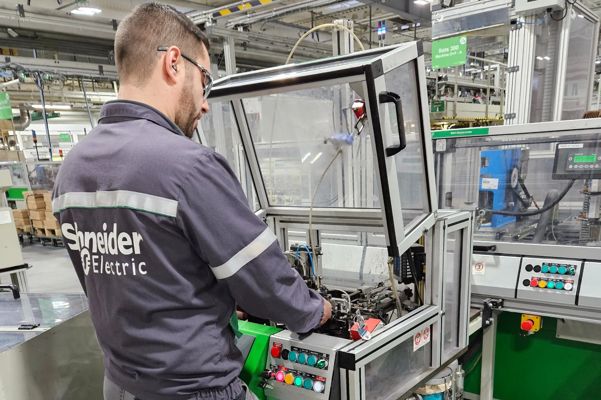 Schneider Electric employee in uniform operating machinery inside a warehouse