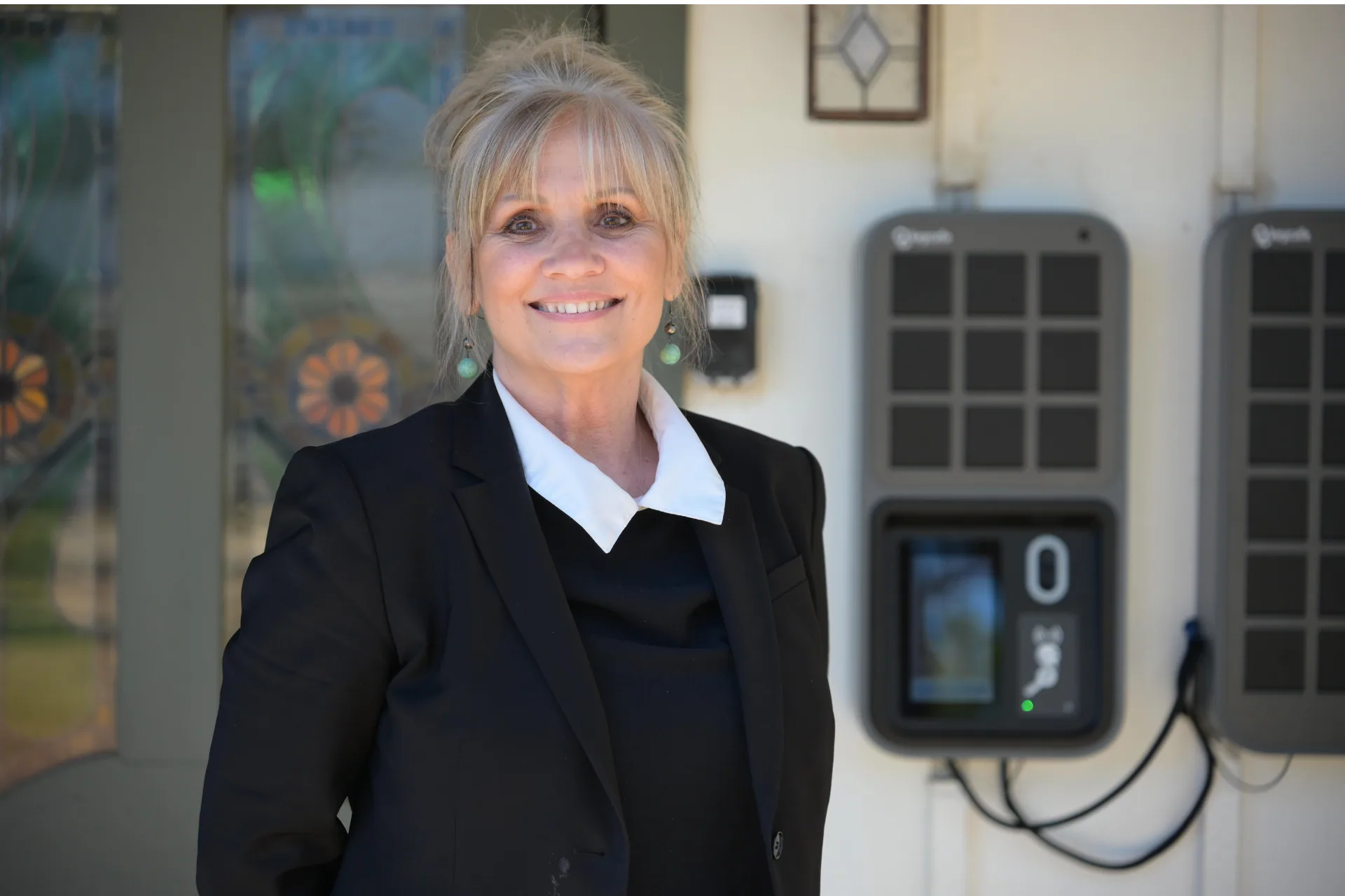 A smiling blonde woman in a black blazer standing next to a Keycafe Smartbox.