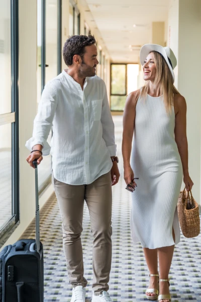 Two short-term rental guests in a building hallway with a suitcase