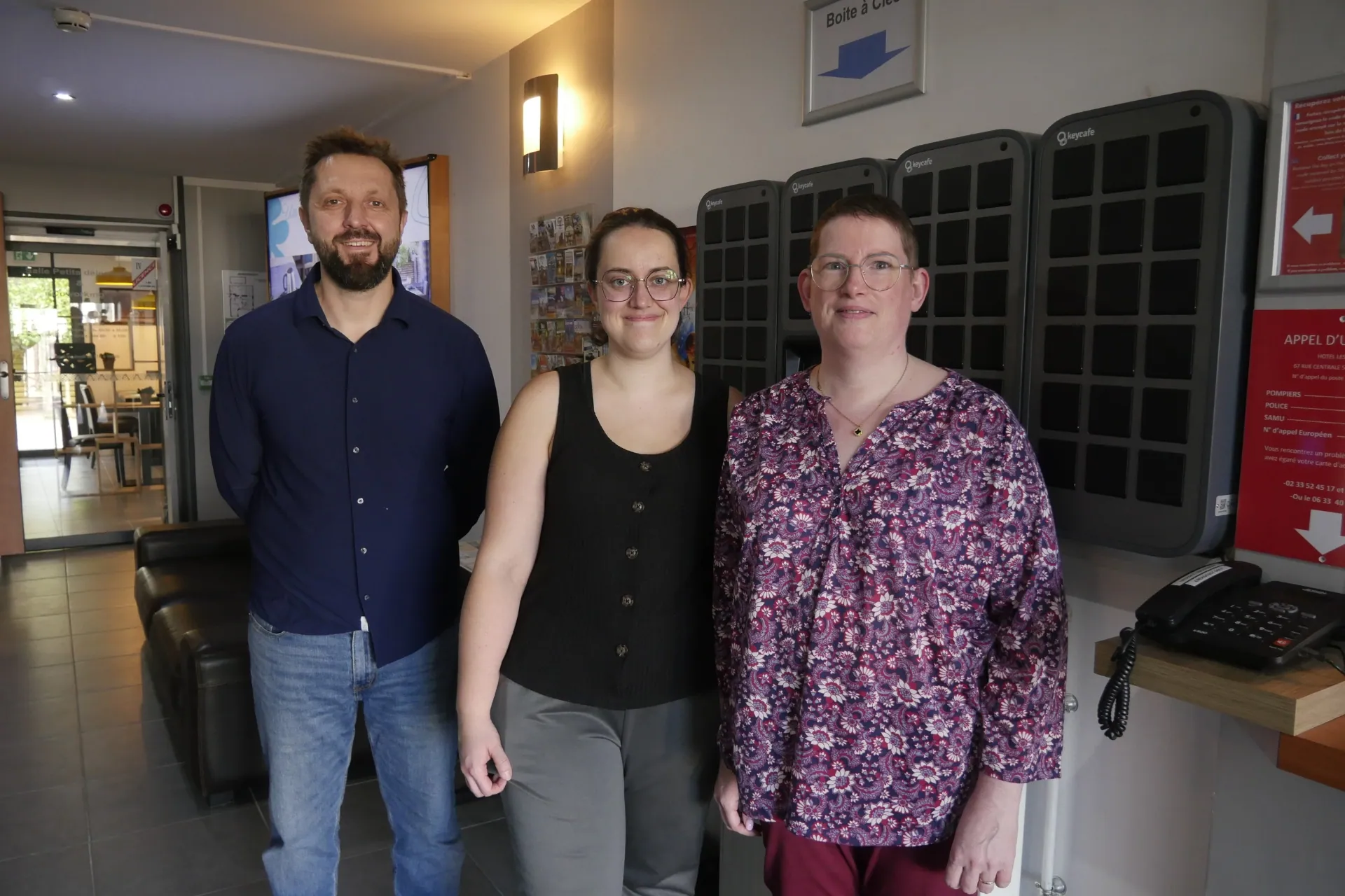 Hôtel les Pieux staff standing in front of their SmartBox setup in the hotel lobby