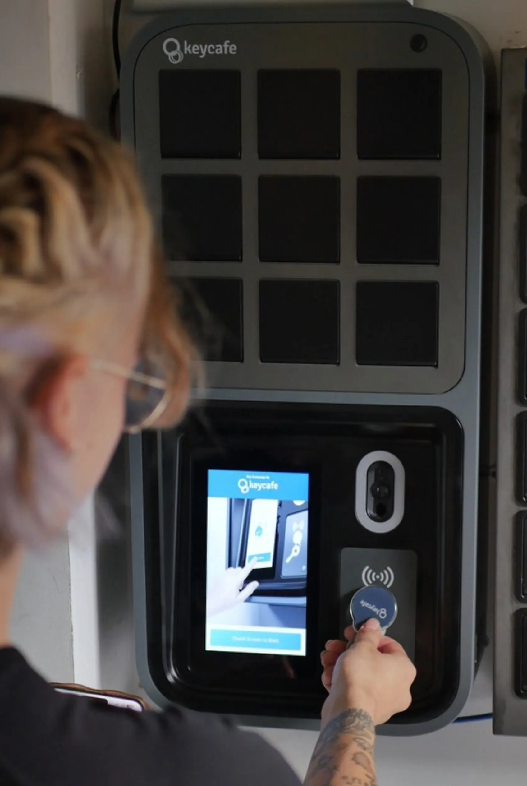 Keycafe smart key locker system being unlocked with a key fob at hotel check-in.