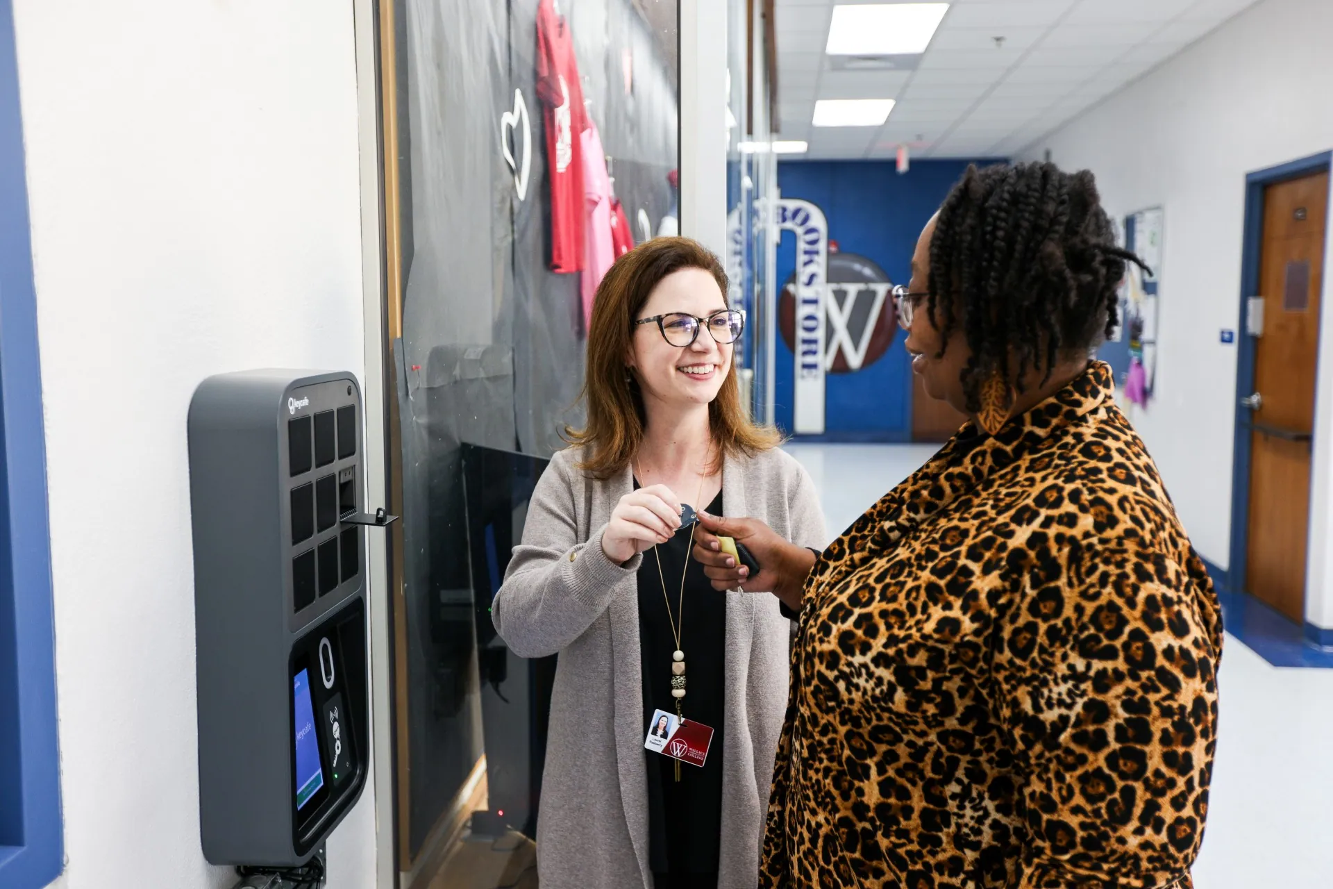 Student and Campus Services Specialist Laurel Rasberry handing keys to another employee beside the SmartBox