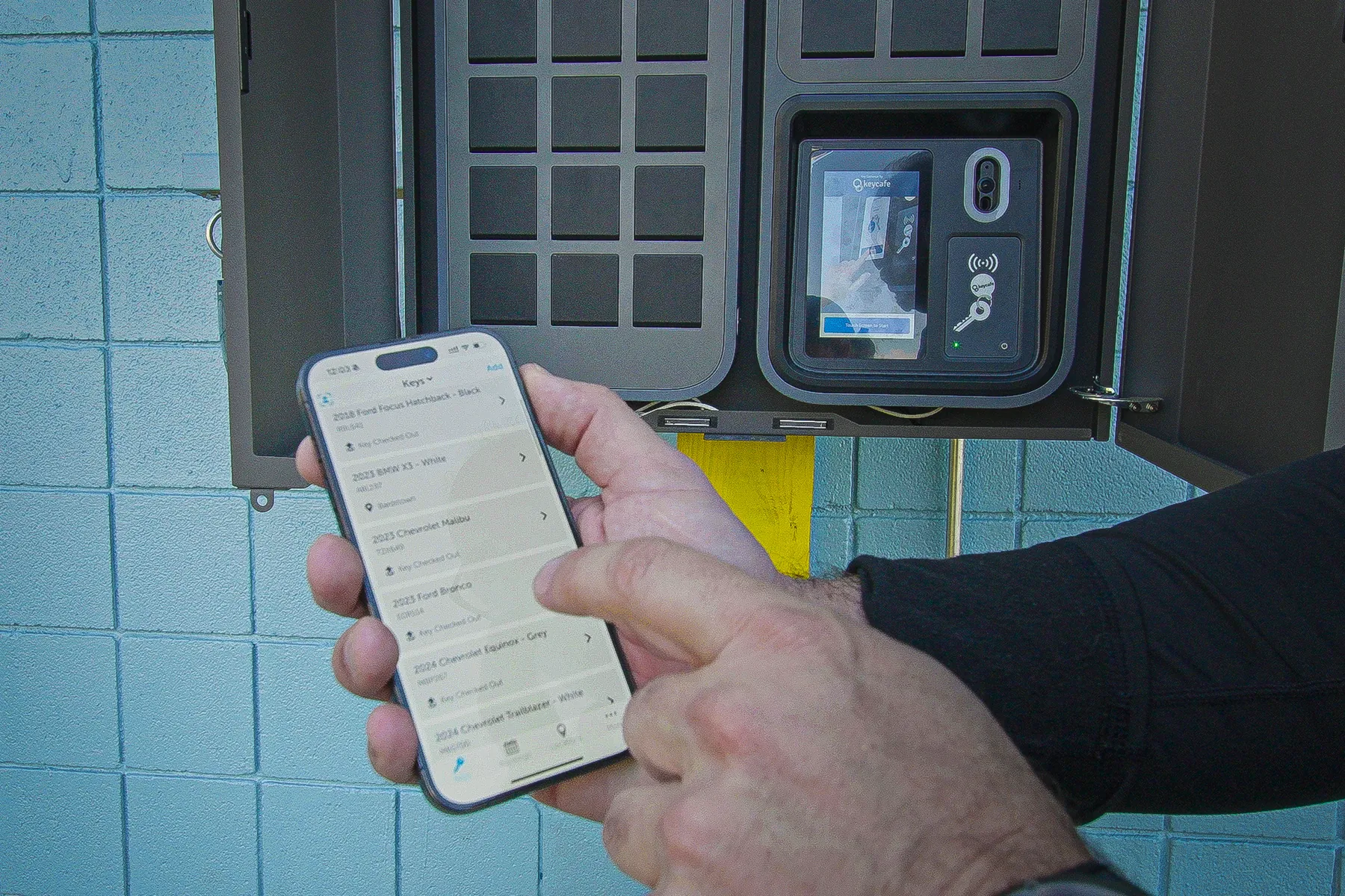 Close up of a hand holding a phone with the Keycafe app next to the SmartBox